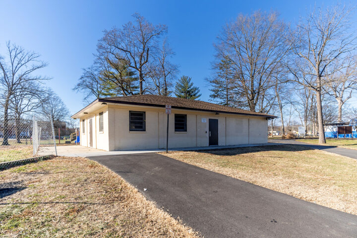 Sunny exterior view of a single-story beige building with an asphalt driveway