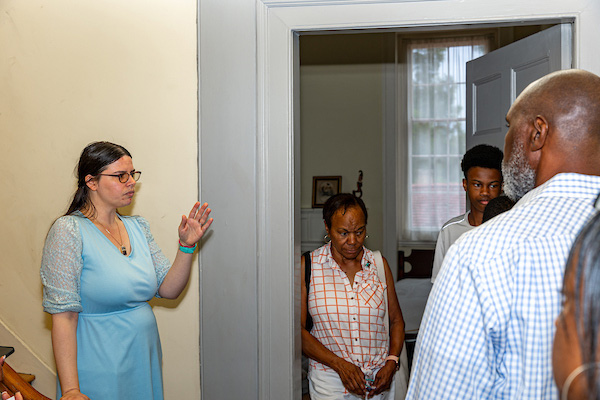 A guide speaks to several visitors standing near the stairs in a historic building.