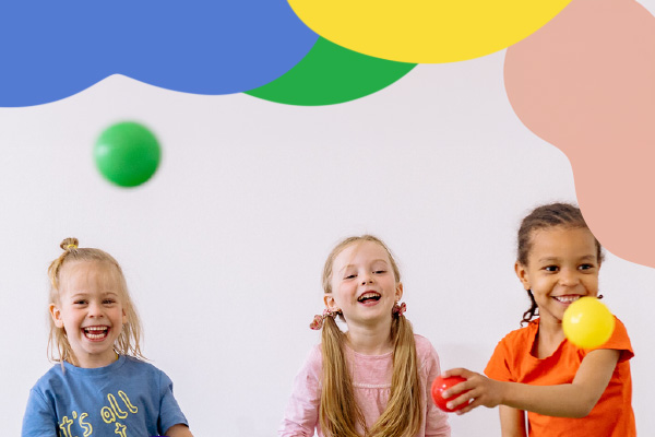 Three smiling kids play with plastic balls.